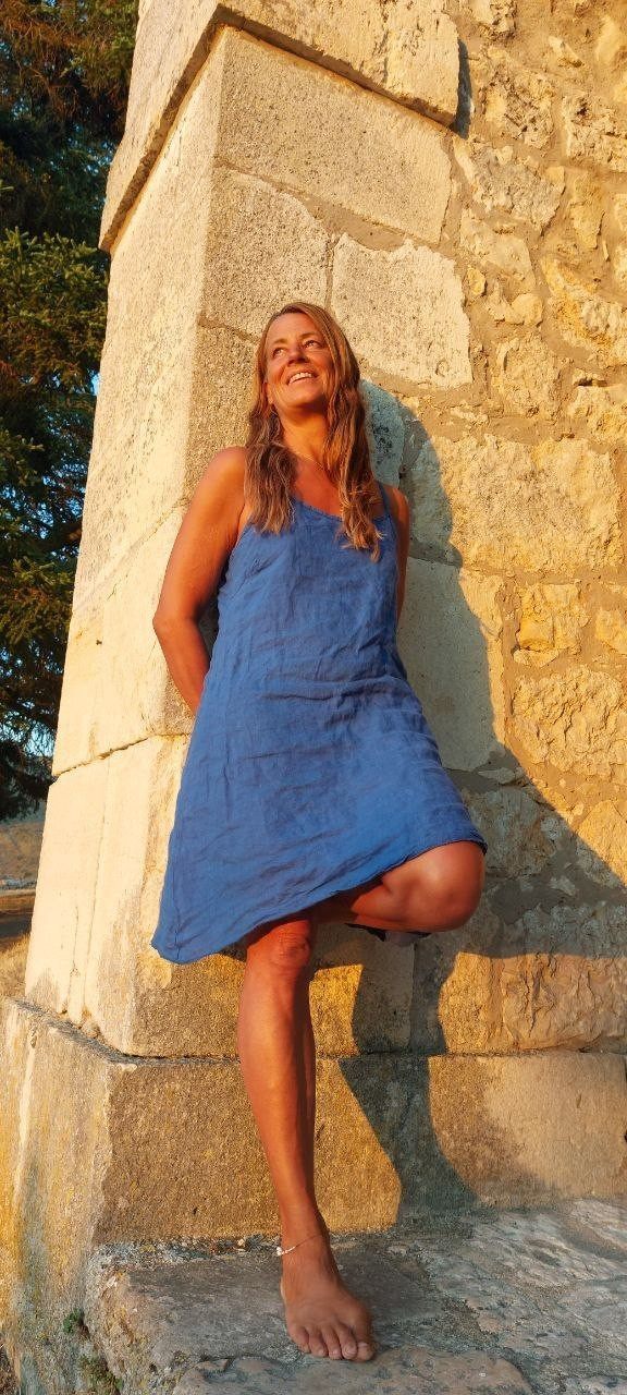 Indira in einem blauen Kleid an einer historischen Steinmauer